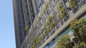 Een hoog gebouw met meerdere balkons, waarvan sommige beplant zijn.