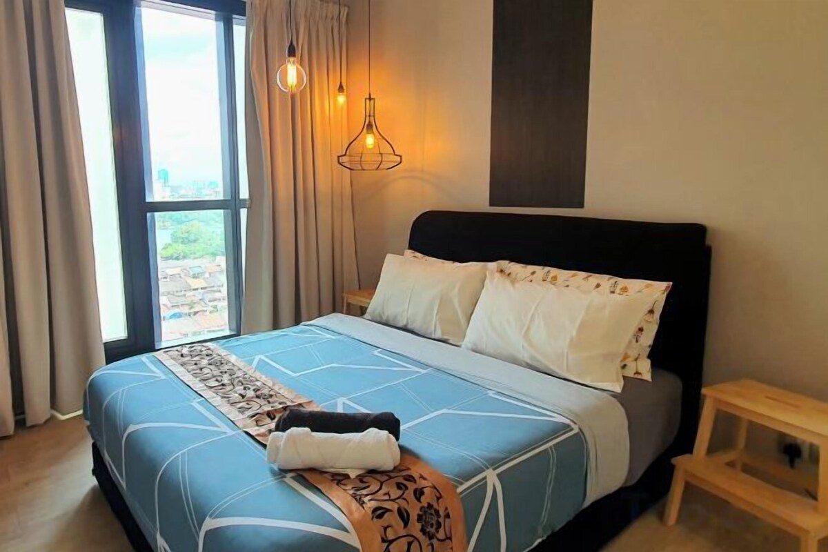 Een slaapkamer met een bed, gordijnen, een nachtkastje en uitzicht door een raam.