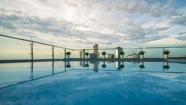 A rooftop infinity pool with a clear view of buildings and a cloudy sky. - Greenery Hotel (Da Nang)
