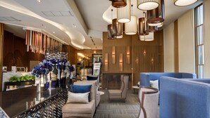 Un vestíbul modern amb zones d'estar, taulell d'informació i il·luminació decorativa.