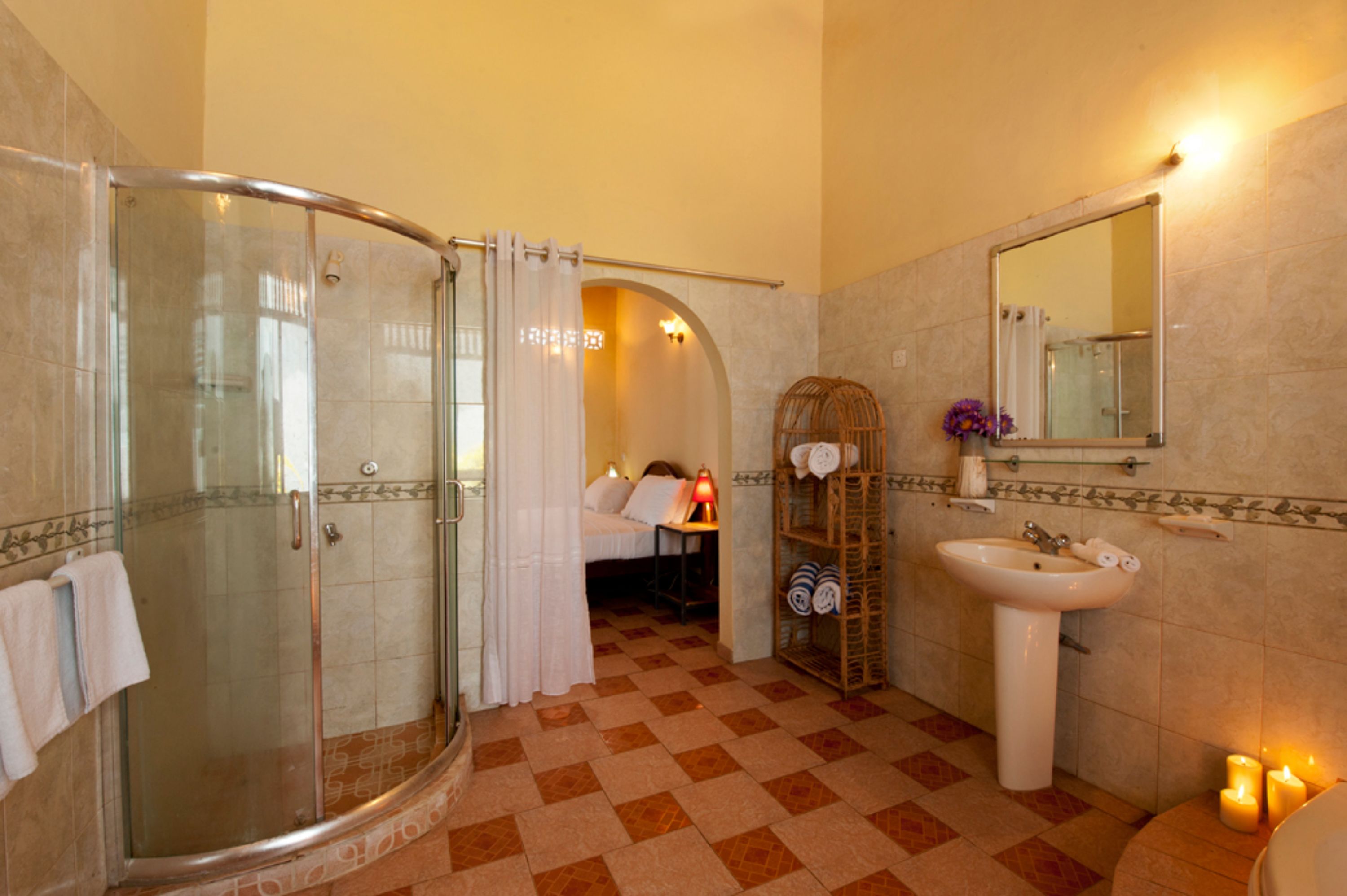 A bathroom with a glass-enclosed shower, a sink, and a mirror.
