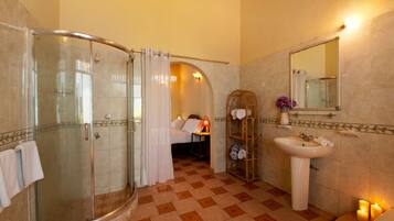 A bathroom with a glass-enclosed shower, a sink, and a mirror.