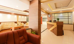 A modern reception area with a sofa, chairs, a reception desk, and a clock on the wall.