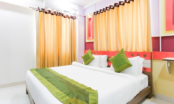 A hotel room with a bed, curtains, and a headboard with a geometric design.