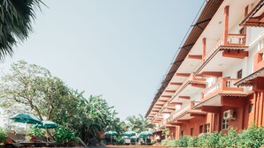 A swimming pool with tiled flooring, surrounded by a building with balconies and air conditioning units. - Chalston Beach Resort (Calangute)