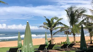 A beachside lounge area with lounge chairs and green umbrellas, overlooking the ocean. - Chalston Beach Resort (Calangute)