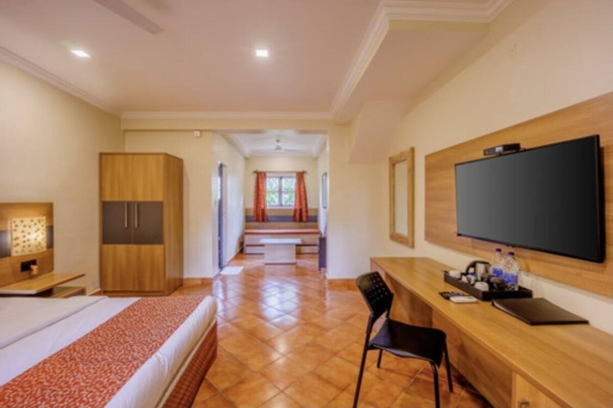 A hotel room with a bed, a desk with a chair, a TV, and a wardrobe.