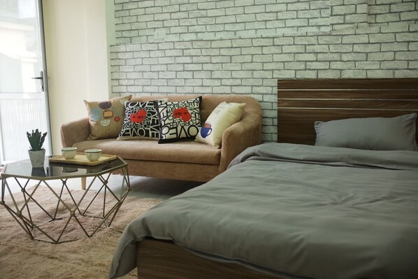 A bedroom with a bed, a sofa, and a coffee table.