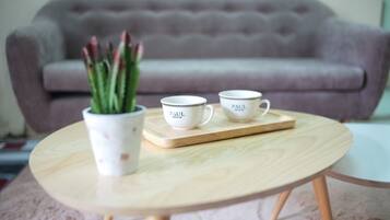 Una mesa redonda de madera con dos tazas blancas que dicen "PAUL" y una planta en maceta con hojas verdes.