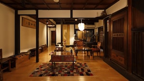 Un intérieur de style japonais traditionnel, avec des planchers en bois, des tatamis et une table centrale entourée de chaises.