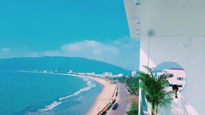 A coastal cityscape with a beach, road, and buildings. - Vivu Hotel (Quy Nhon)