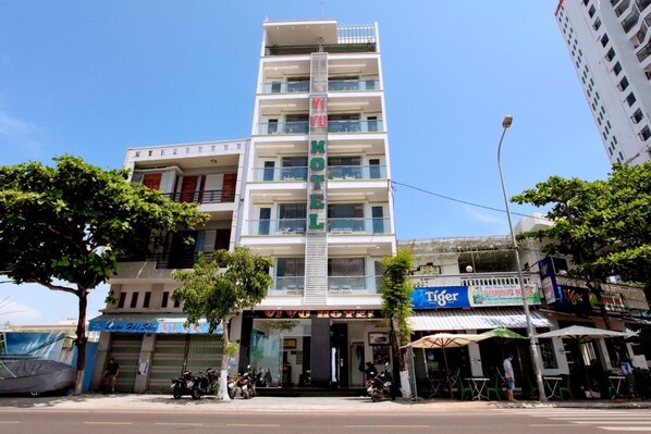 A multi-story hotel with a prominent sign, outdoor seating, and a parked motorcycle.