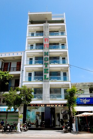 A multi-story hotel with a prominent vertical sign, balconies on each floor, and a storefront with a sign that reads 'TIGER'.