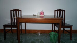 A wooden dining table with two chairs, a tissue box, and a small basket on a tiled floor.