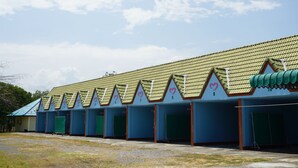 A row of numbered hotel rooms with green doors and a tiled roof.