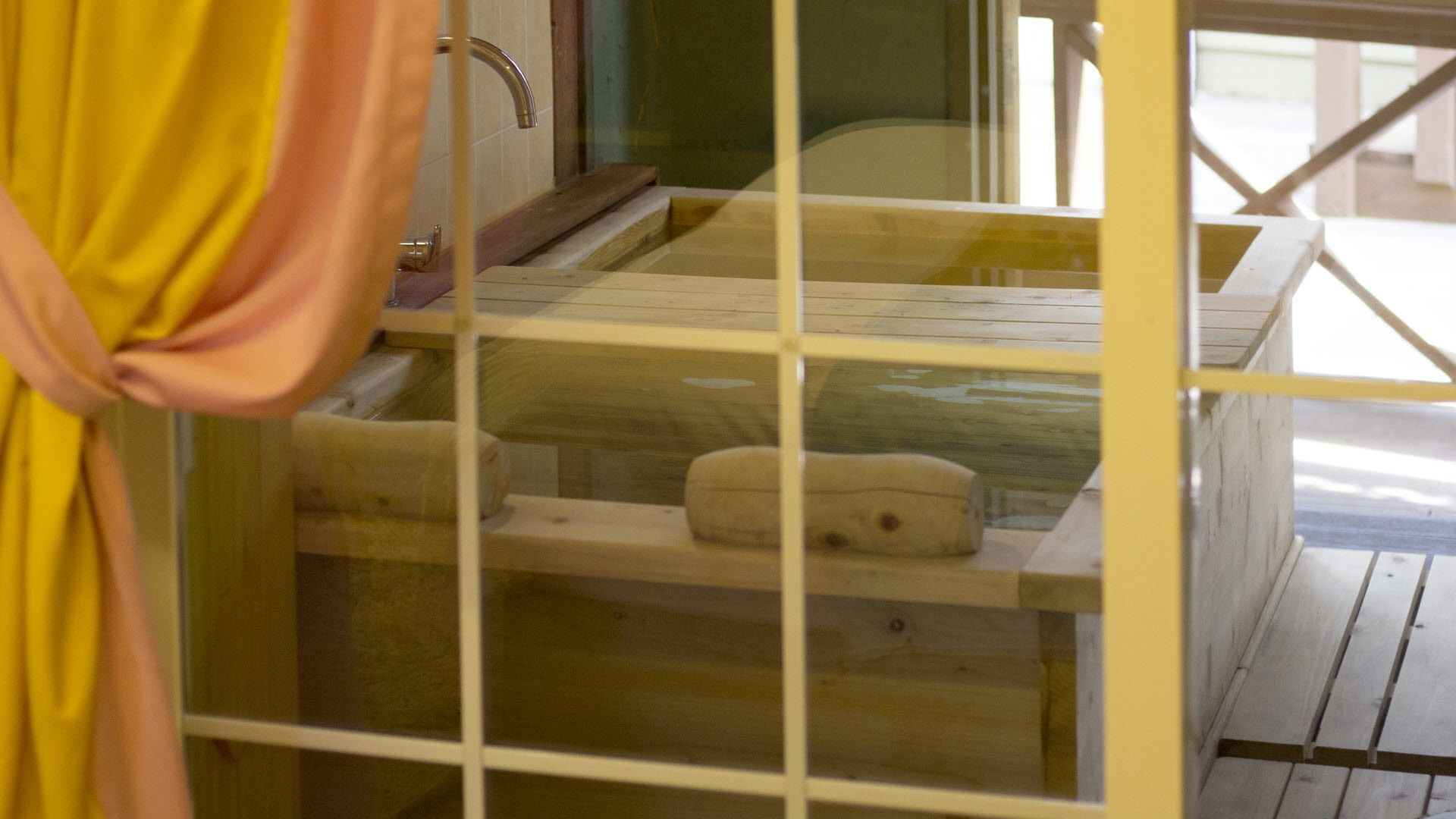 A wooden cabin with a glass enclosure, a wooden bench, and a small table.