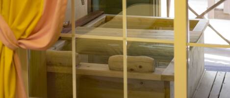 A wooden cabin with a glass enclosure, a wooden bench, and a small table.
