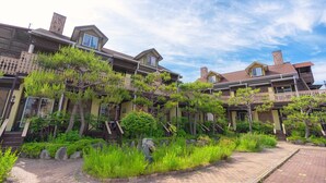 Un edificio residenziale con diversi balconi, un vialetto in mattoni e una vegetazione rigogliosa.