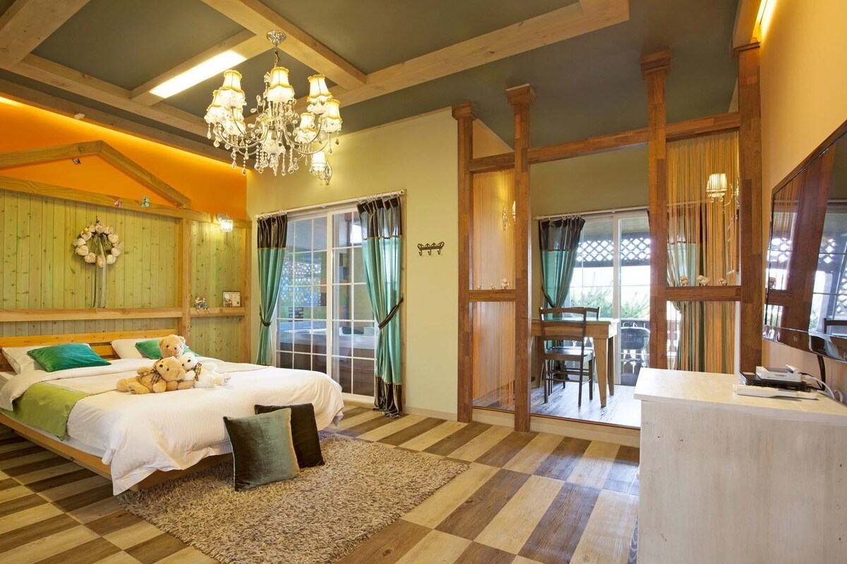 A cozy bedroom with a bed, a desk, and a chandelier.