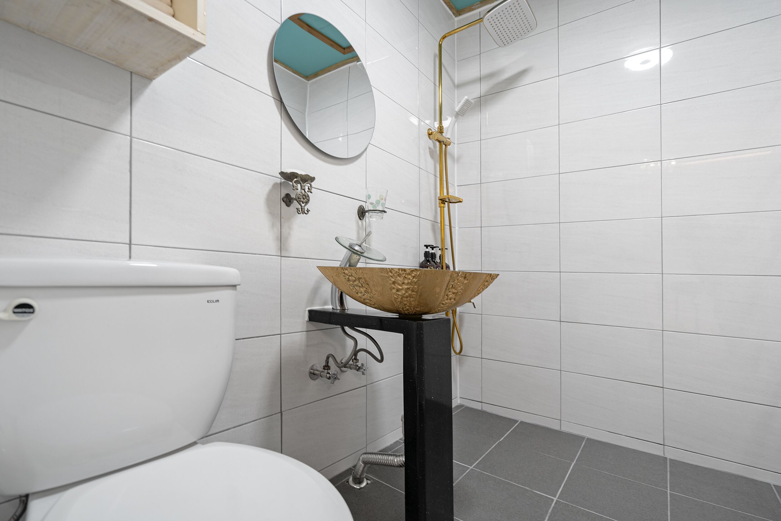 Une salle de bain comprenant des toilettes, un lavabo avec un récipient décoratif, une douche et un miroir au mur.
