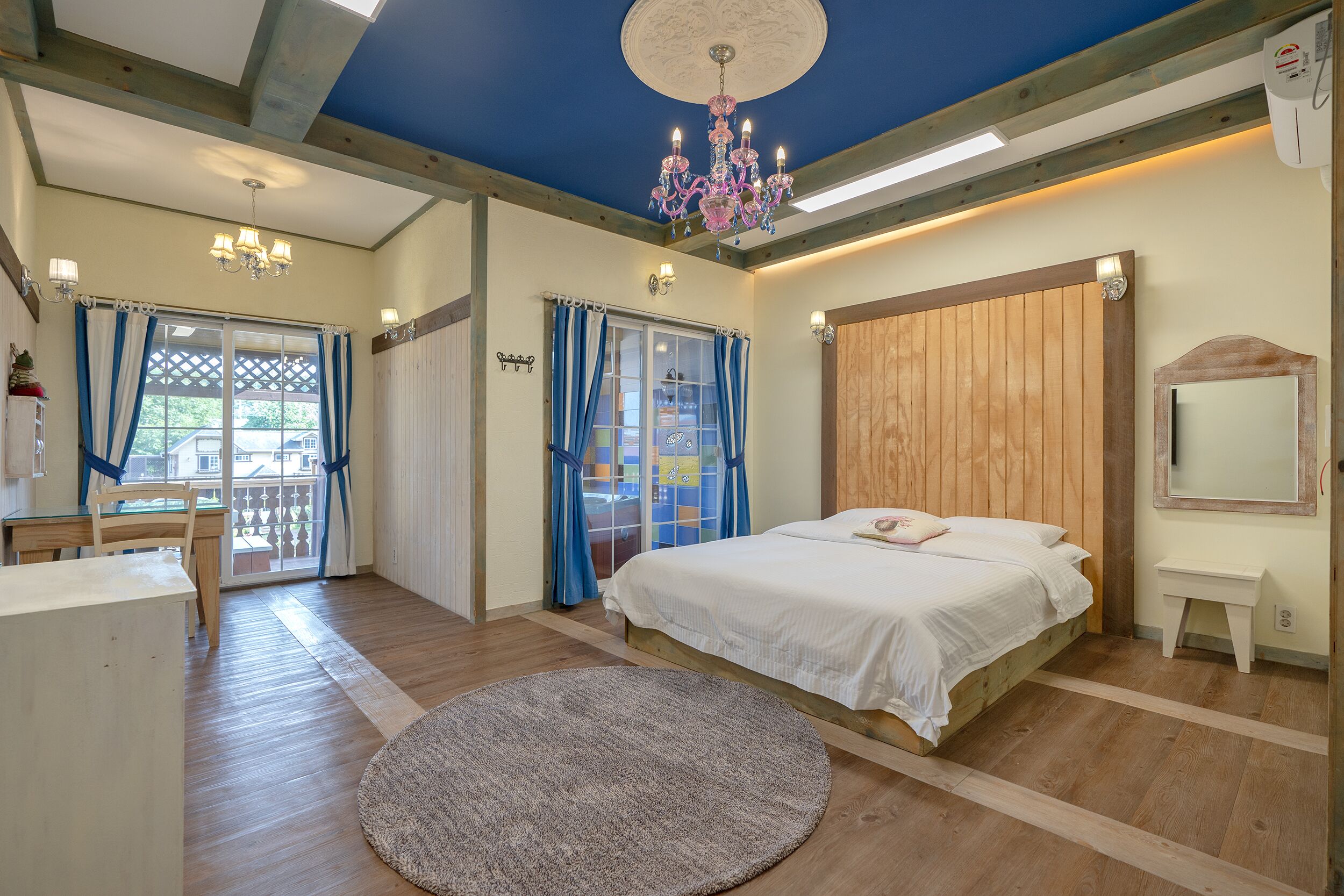Un dormitorio con una cama de madera, un escritorio y una araña.