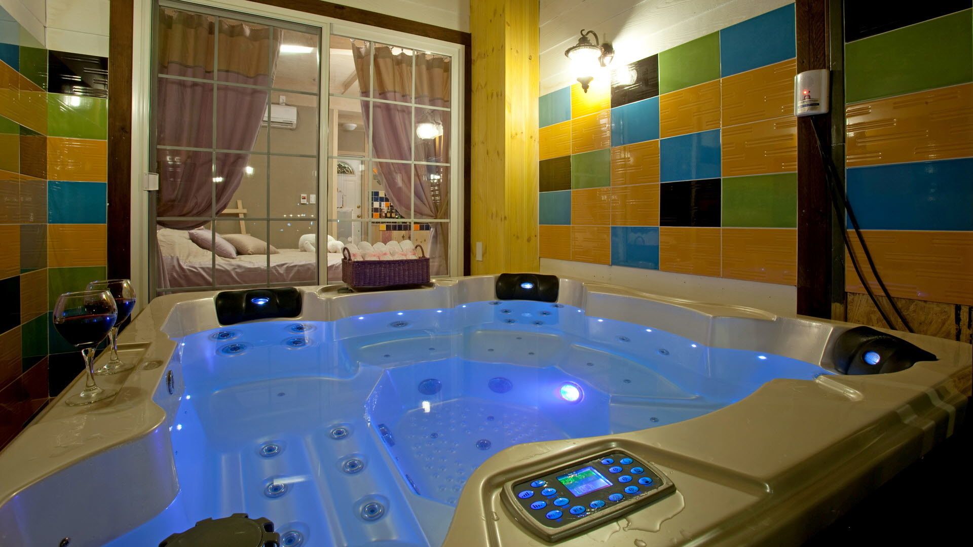 Ein modernes Badezimmer mit einer großen Badewanne, einer Bedienkonsole und einem Fenster mit Vorhängen.