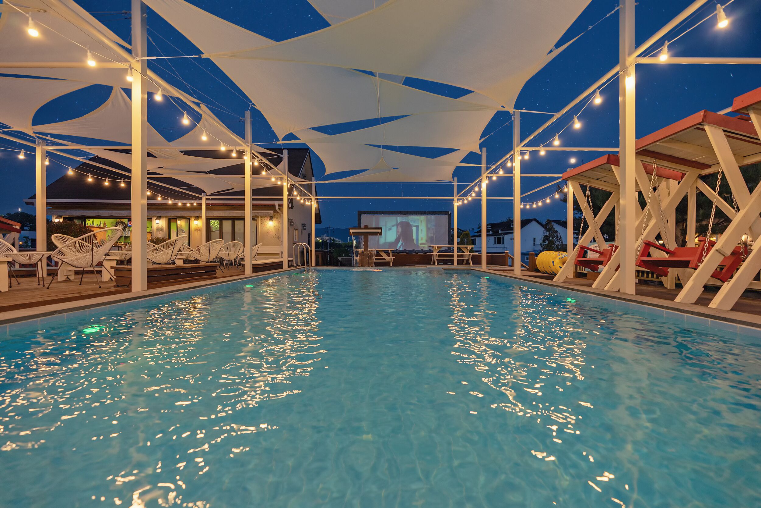 A swimming pool with a ceiling structure and string lights.