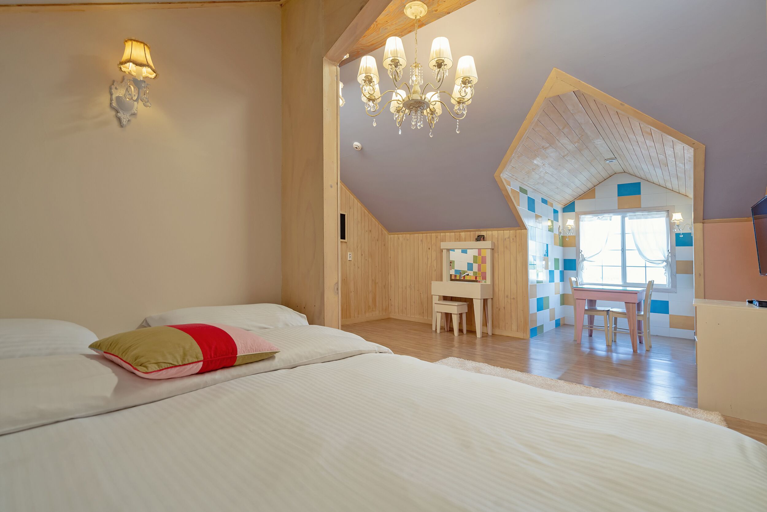 Un dormitorio con dos camas, techo de madera, candelabro, escritorio y ventana con vistas.