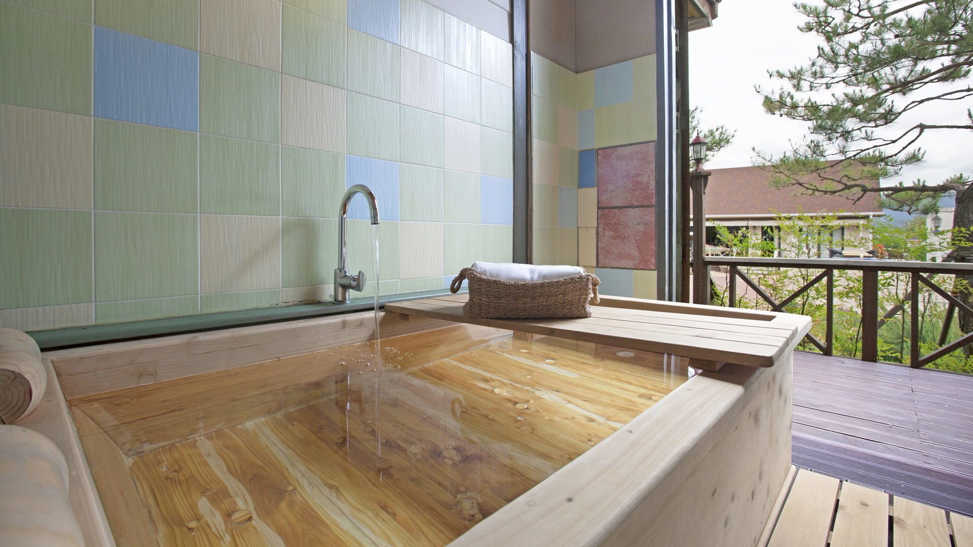 Una bañera de madera con un grifo, un bolso tejido y vistas al exterior por una ventana.