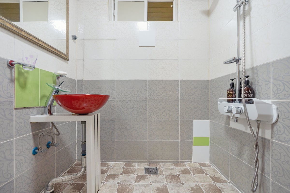 A bathroom with a sink, mirror, shower, and patterned tiles.