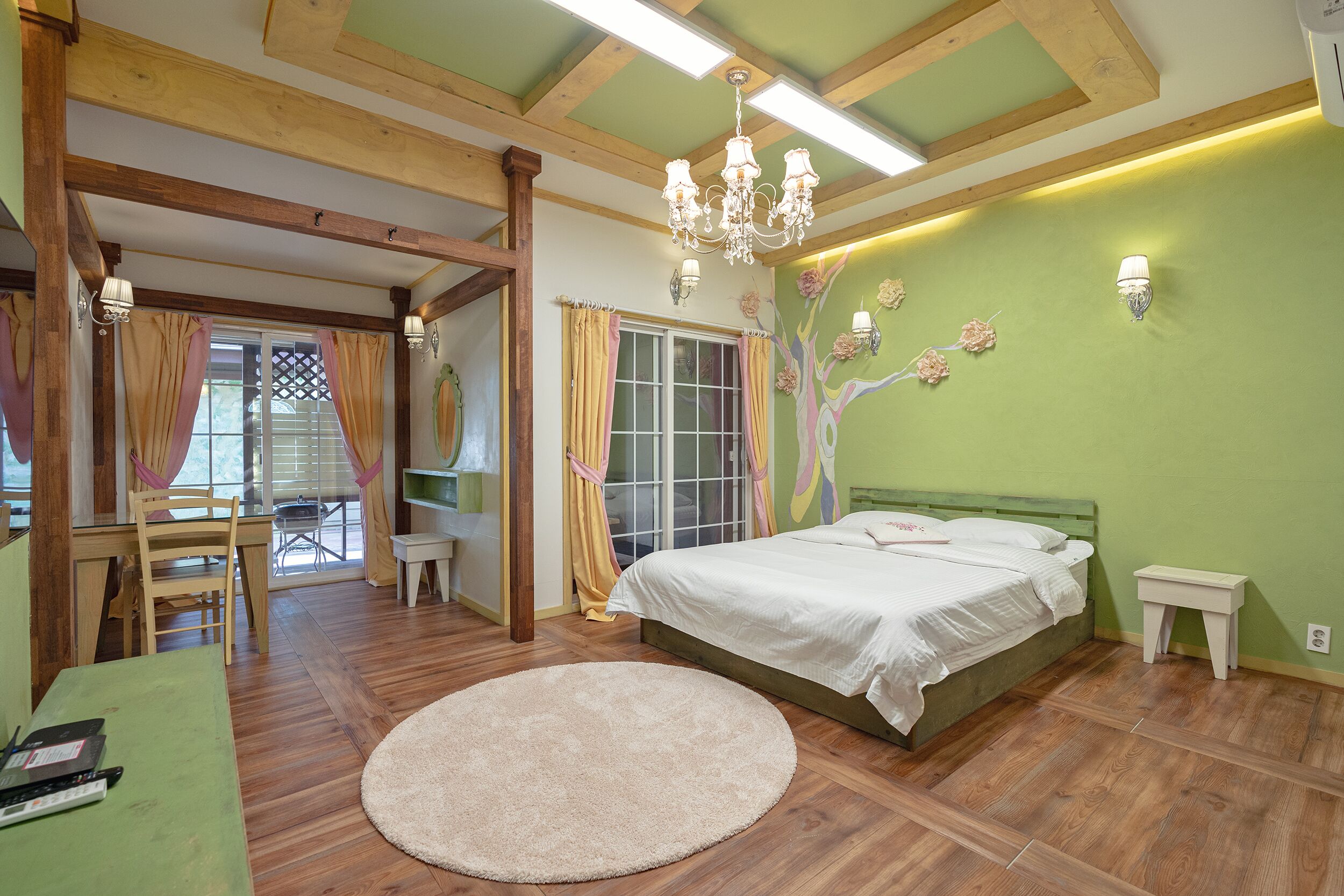 A bedroom with a bed, a round rug, a desk, and a chair.
