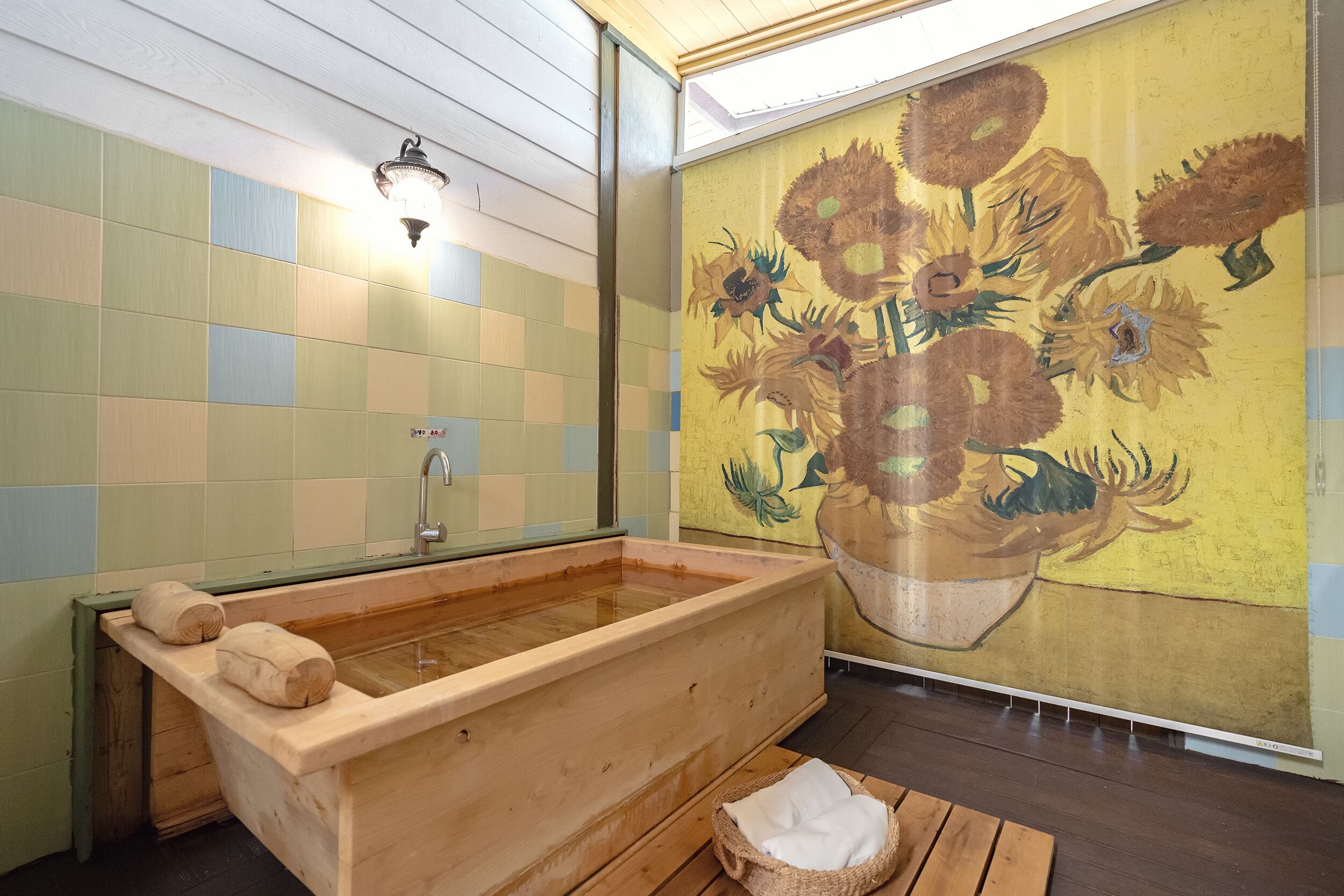 A wooden bathtub in a room with a checkered tile wall and a sunflower mural.