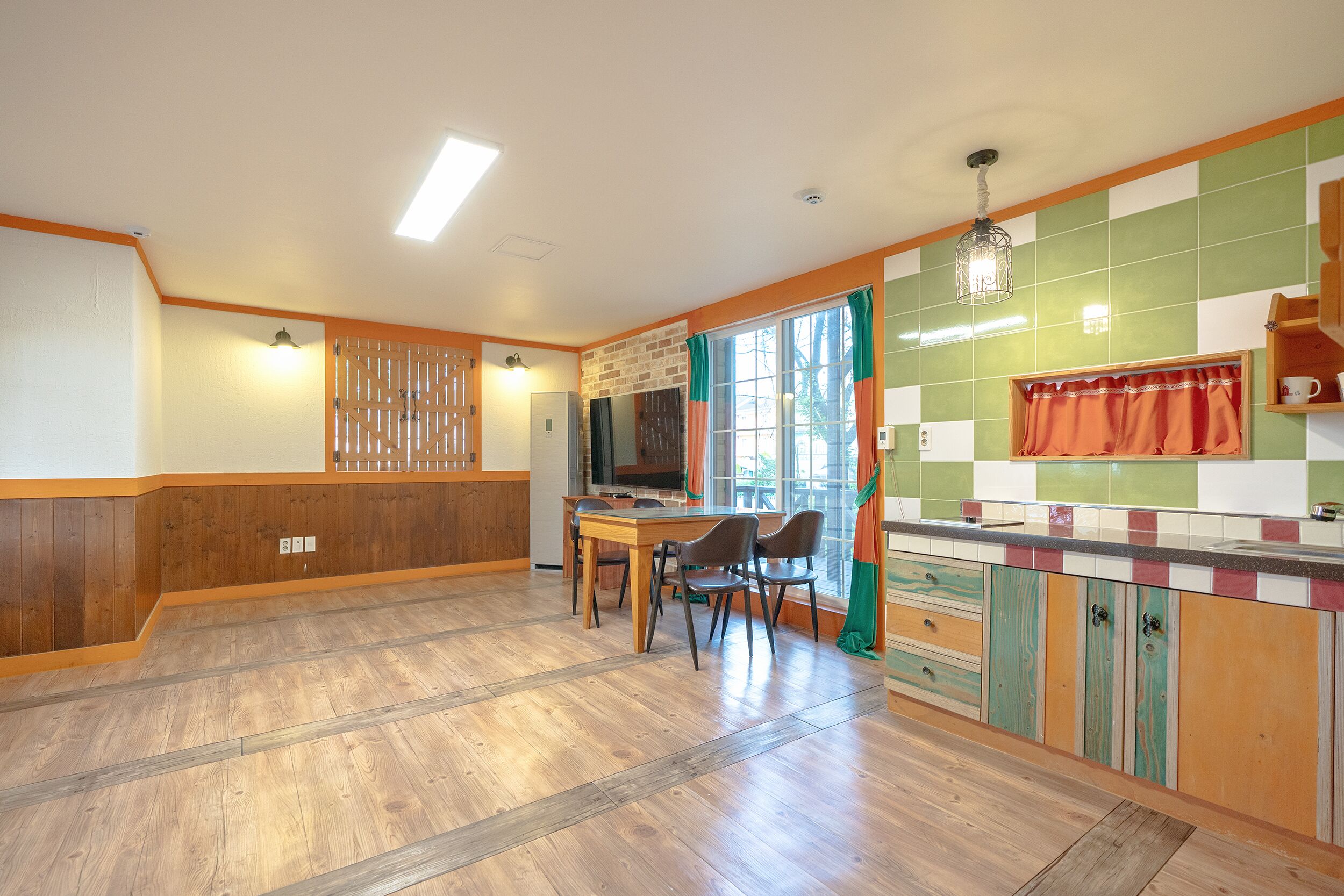 A kitchen with a dining table and chairs, wooden cabinets, and a window with curtains.