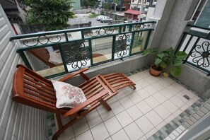 Un balcon avec deux chaises en bois, une plante en pot et une vue sur la rue.