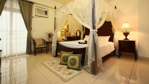 A bedroom with a four-poster bed, a bedside table with a lamp, a chair, and a decorative rug. - Hope Sea Bed and Breakfast (Hualien City)