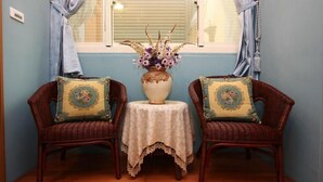 Two wicker chairs with floral cushions, a small table with a lace tablecloth, and a vase with flowers. - Hope Sea Bed and Breakfast (Hualien City)