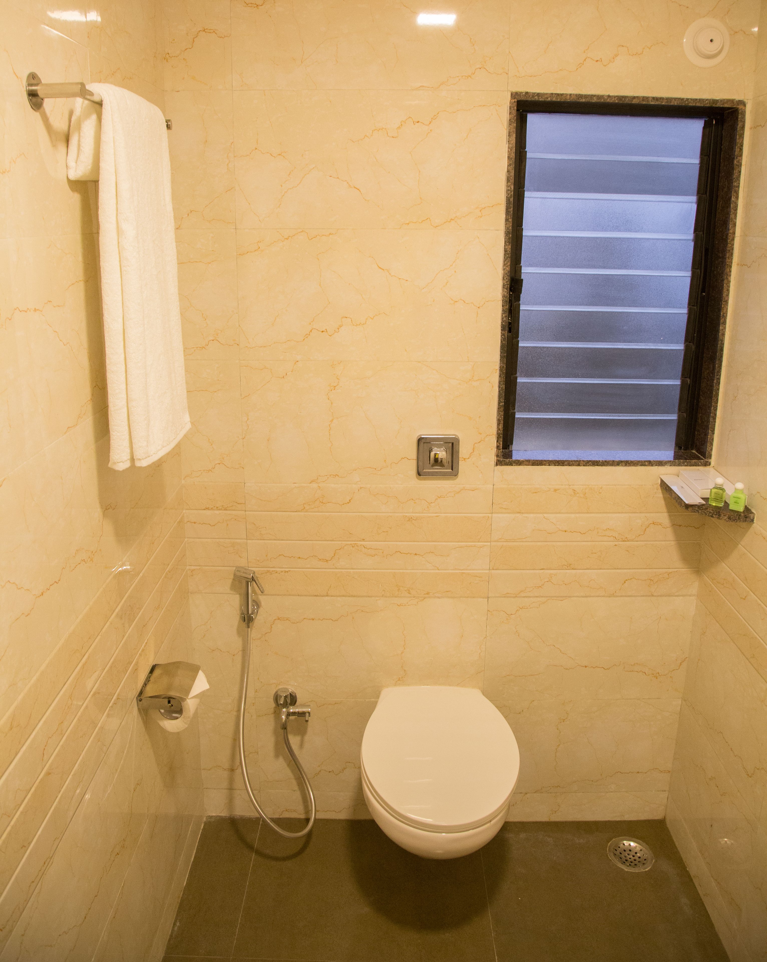 A small bathroom with a toilet, a shower, and a window.