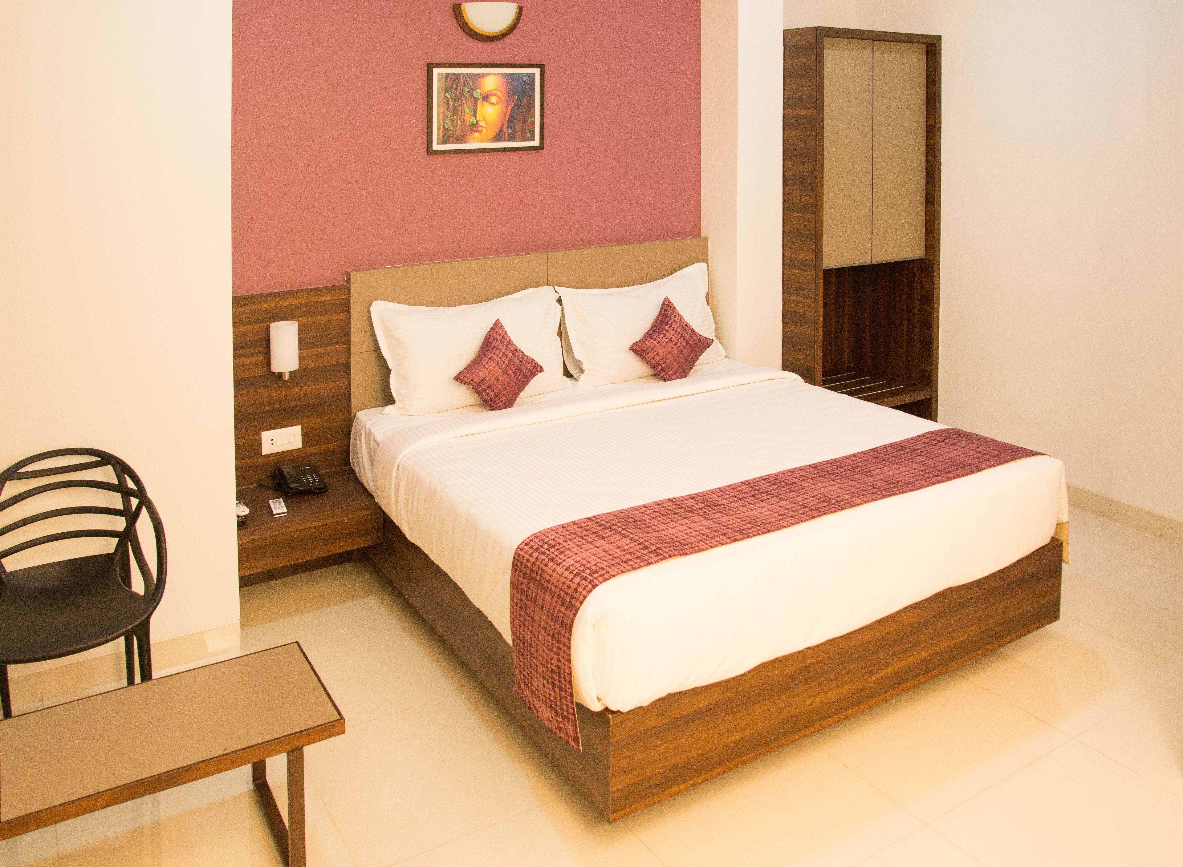 Une chambre d’hôtel bien aménagée, avec un grand lit, une table de chevet avec une lampe, une chaise et une armoire.