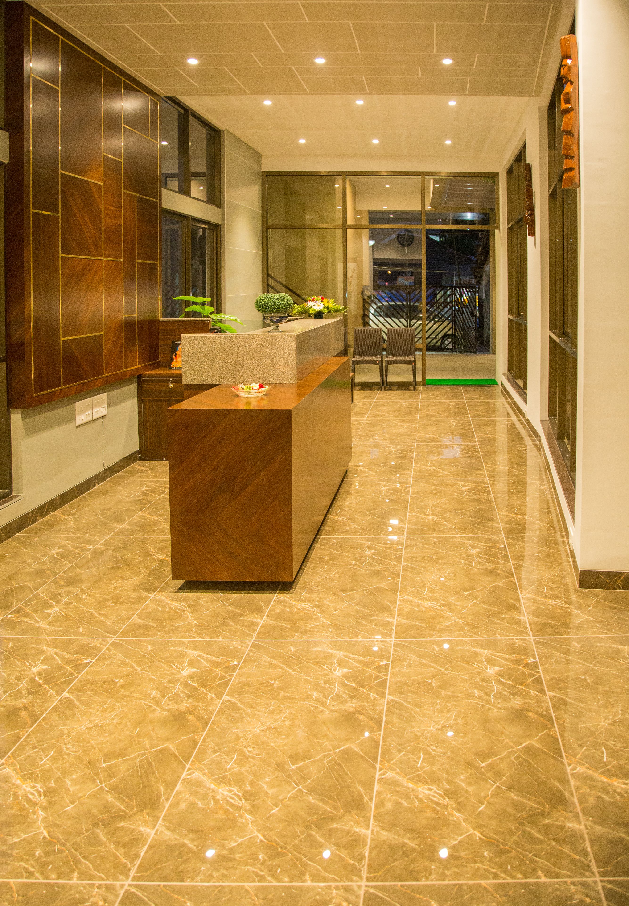 A reception area with a marble floor, a reception desk, and a staircase leading to an upper level.