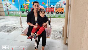 A woman and a child on a swing with a colorful mural in the background.