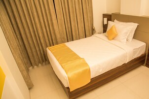 A neatly made bed with a yellow throw blanket, a wooden headboard, and a bedside lamp.