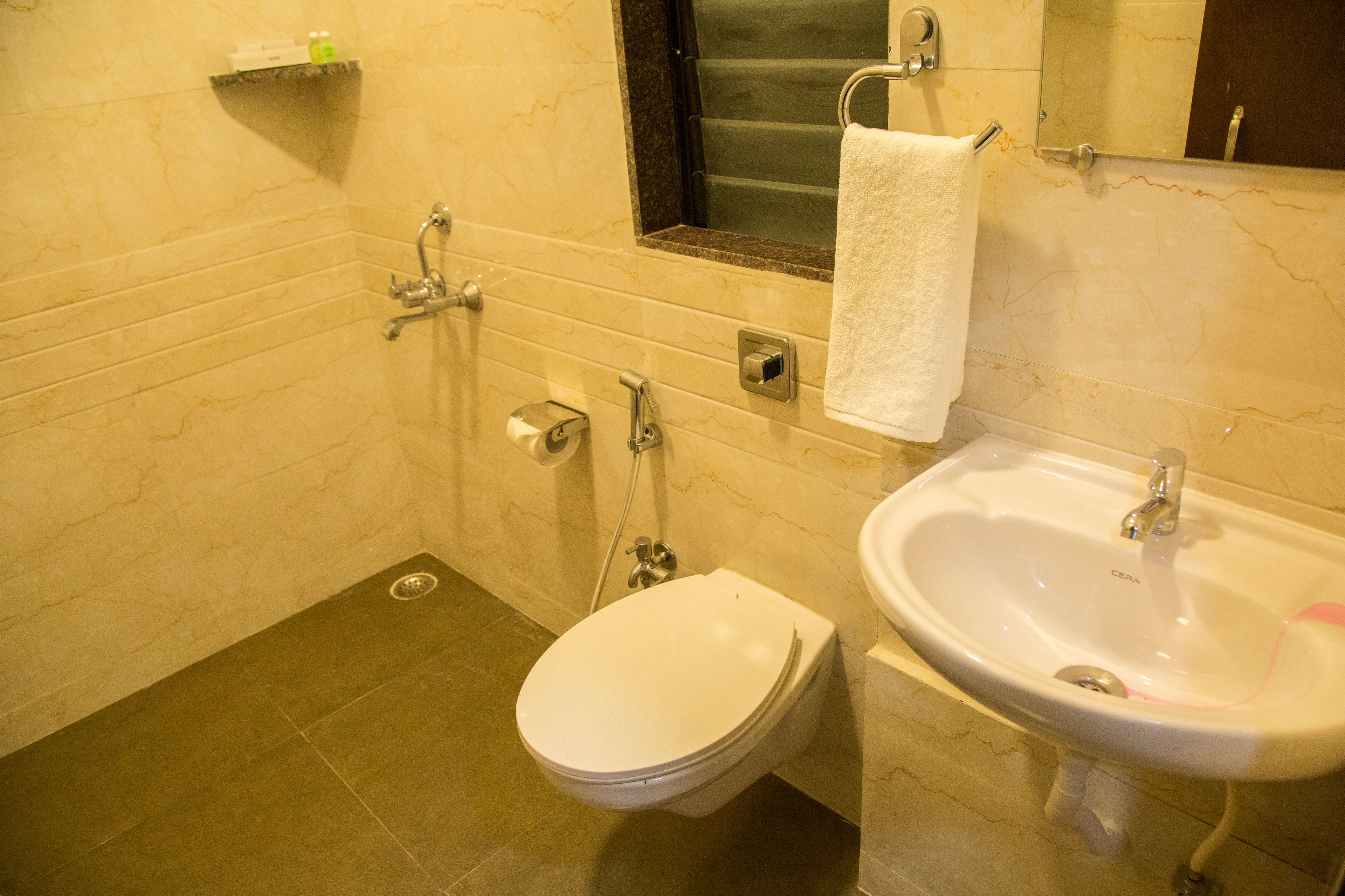A bathroom with a toilet, sink, and mirror.