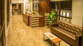 A lobby with a reception desk, a sofa, a coffee table, and a plant.