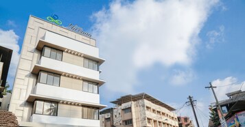 A modern hotel building with a prominent logo at the top.