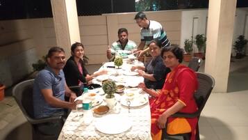 A group of people seated around a table with plates, bowls, and a small potted plant.