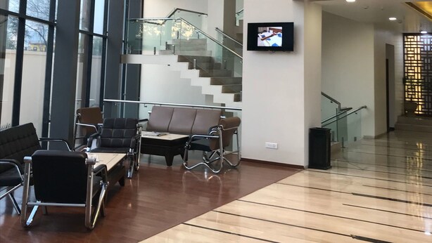 Tilava aula, jossa on korkea katto, moderni portaikko ja oleskelualue.