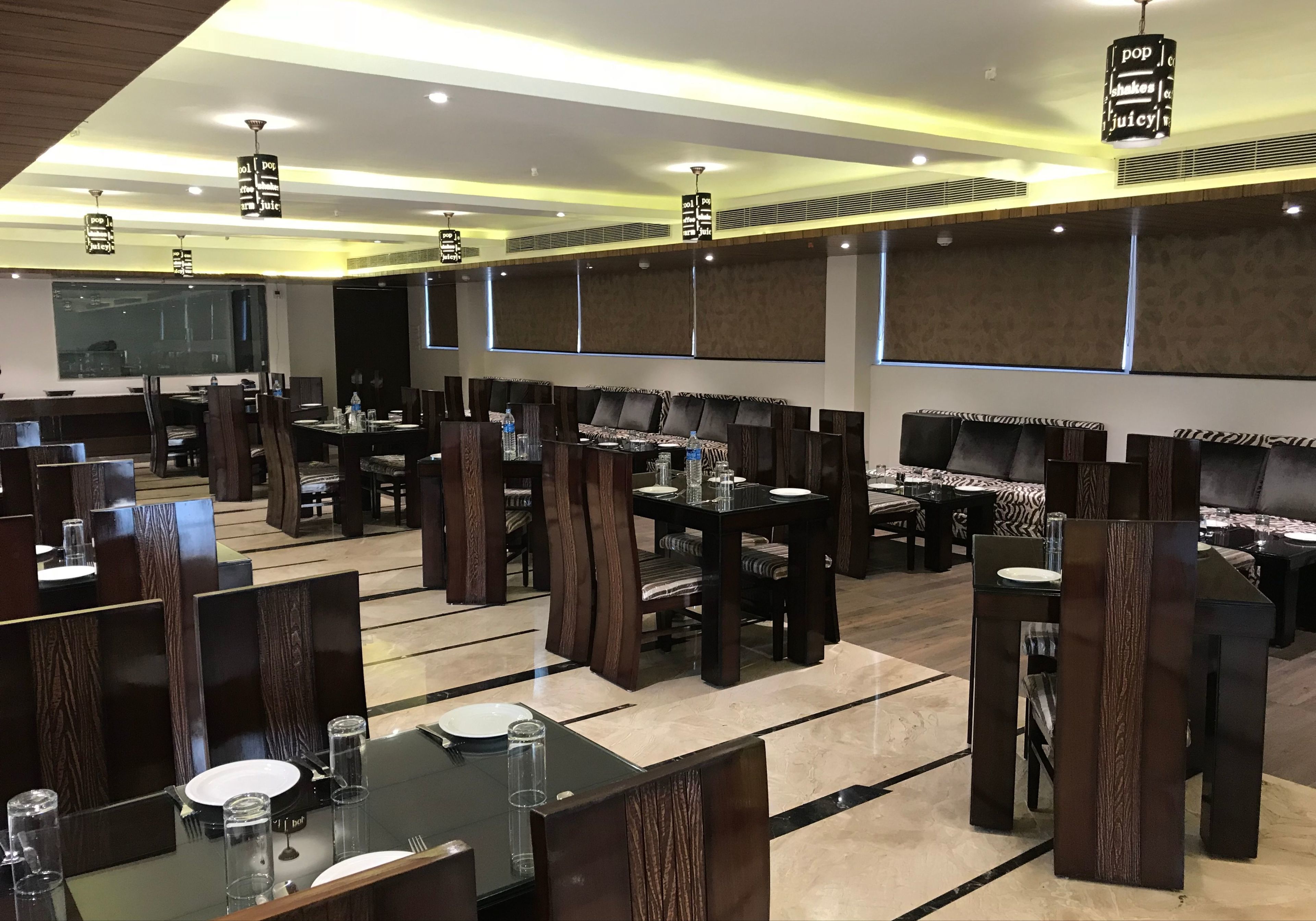 A restaurant with multiple dining tables and booths, each with a dark wood finish and cushioned seating.