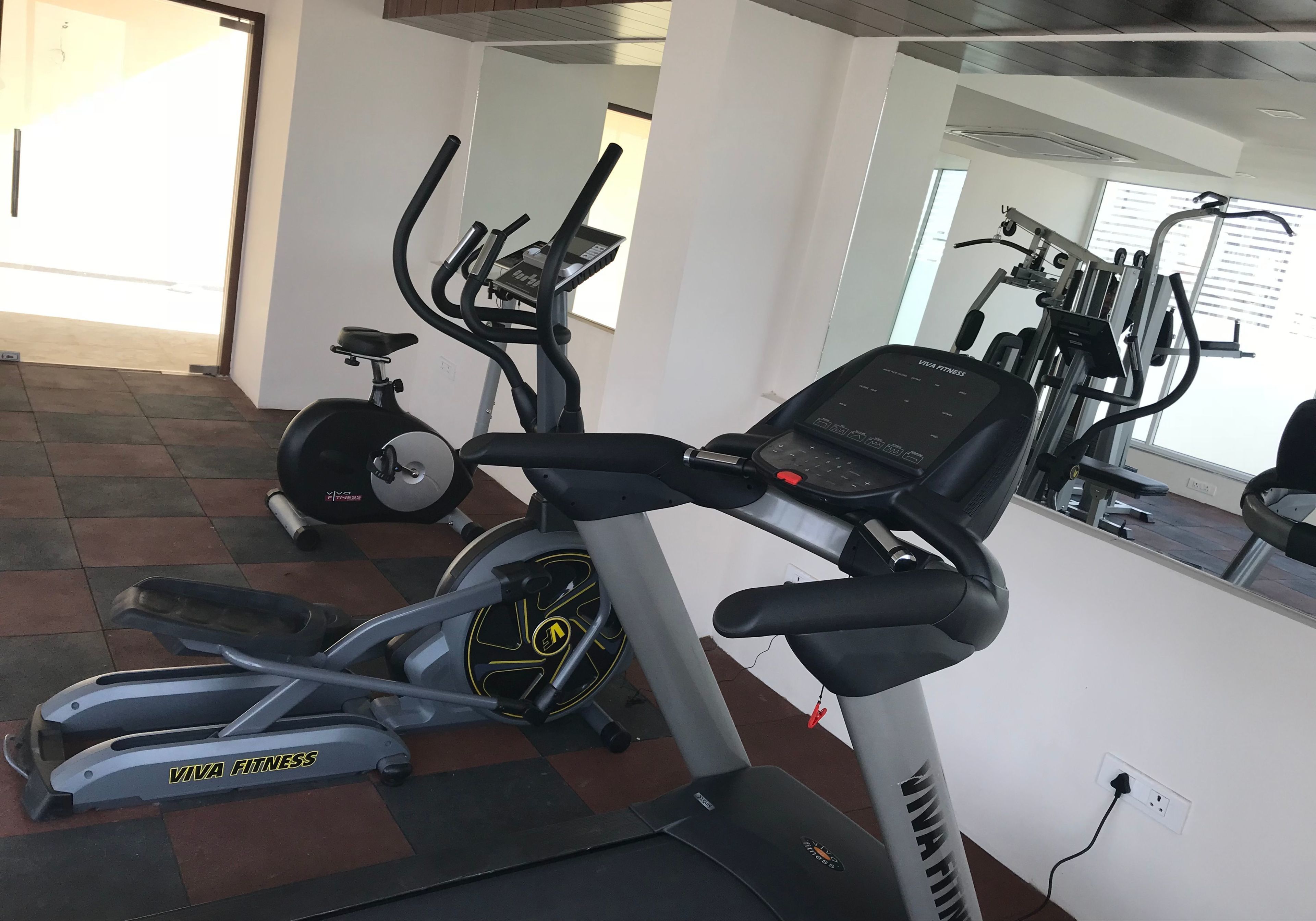 Een fitnessruimte met cardioapparatuur, waaronder een loopband, hometrainer en vastzetfiets.