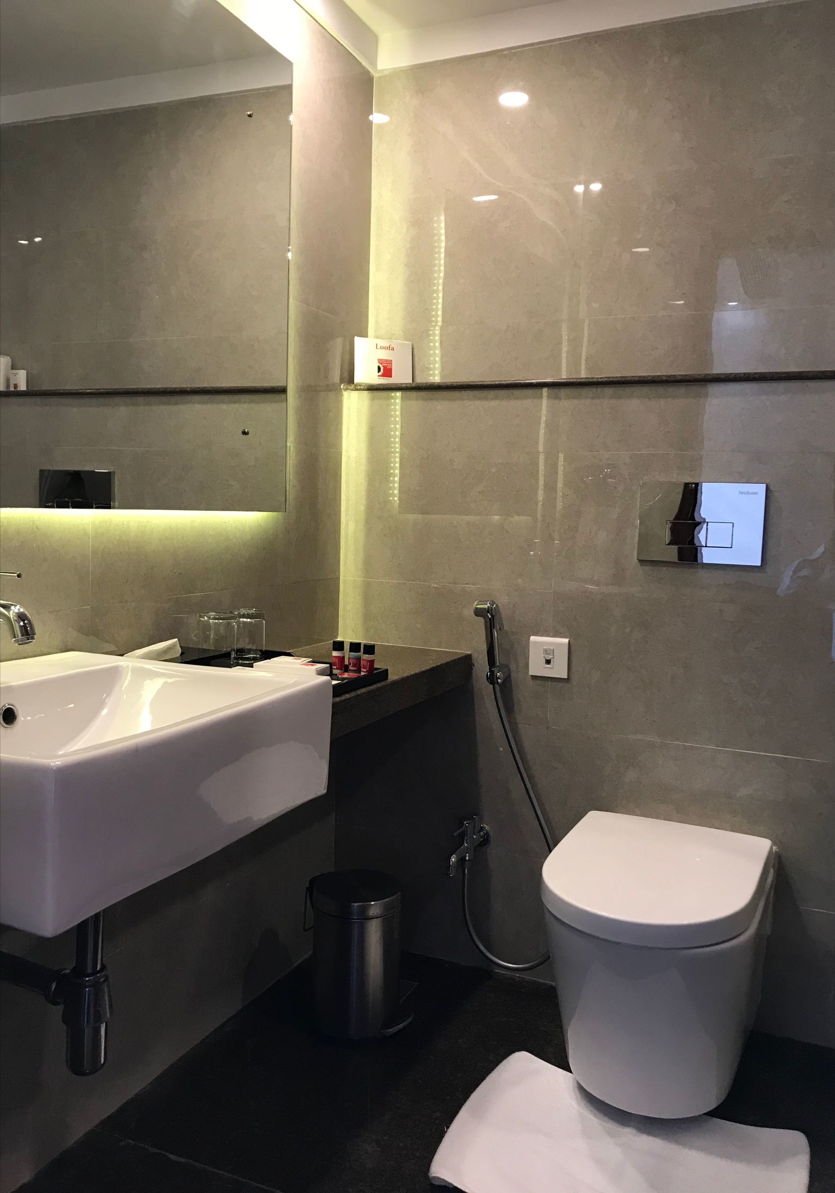Ein modernes Badezimmer mit einem großen Waschbecken, einem Spiegel und einer Toilette.