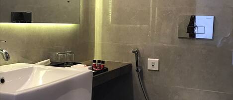 Ein modernes Badezimmer mit einem großen Waschbecken, einem Spiegel und einer Toilette.